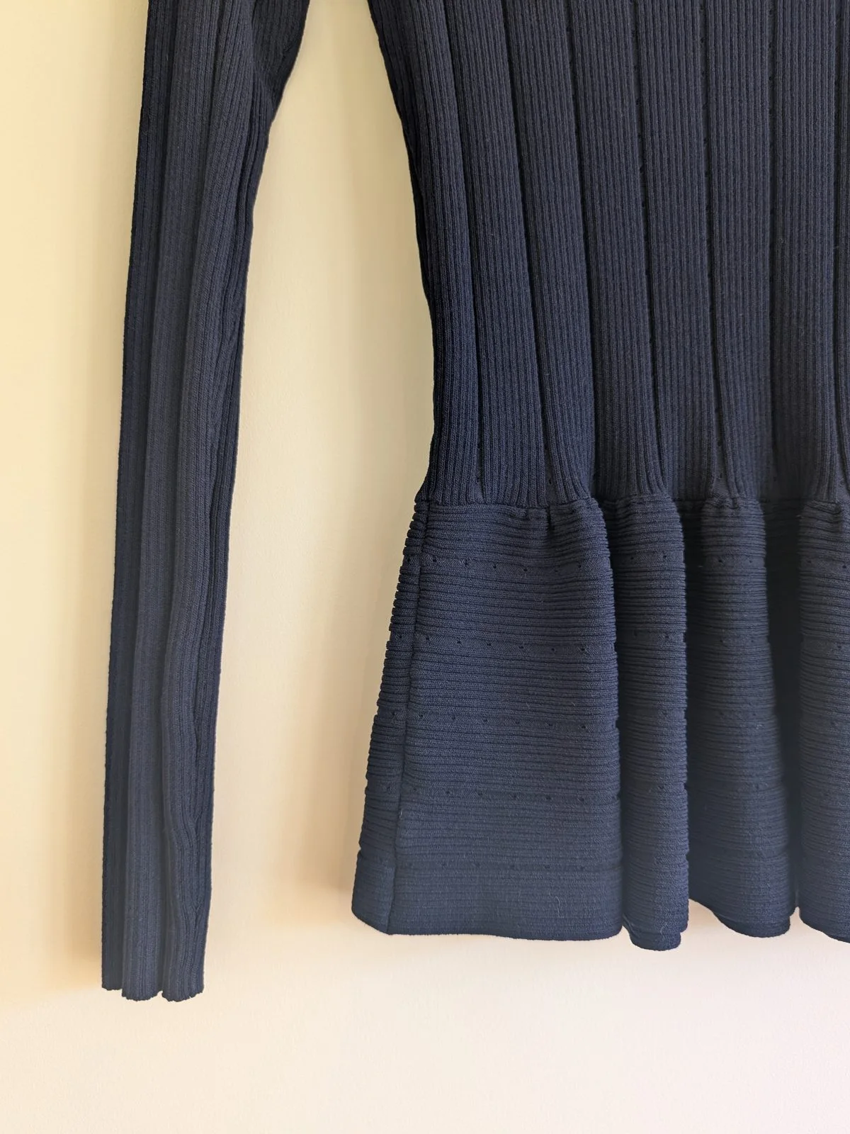 Close view of the peplum hem and left sleeve